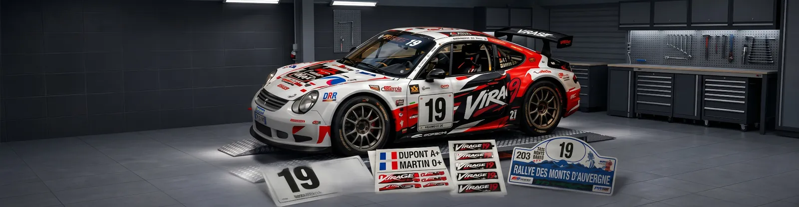 Voiture de rallye Virage 19 en atelier, entourée de numéros de course, de planches de stickers d’équipage et d’une plaque de rallye